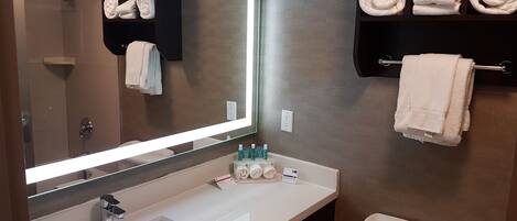 A bathroom with a mirror, sink, towel rack, and a toilet.
