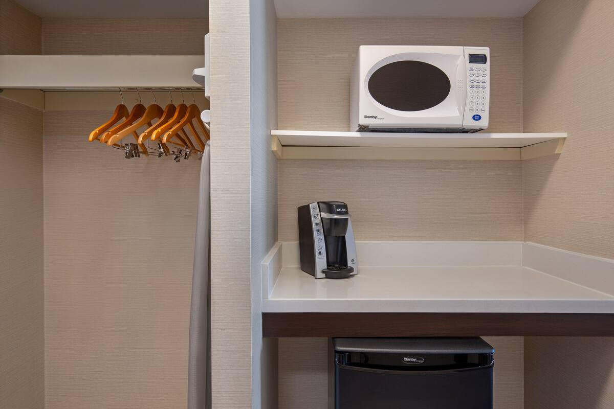 Une petite cuisine équipée d’un four à micro-ondes, d’une machine à café et d’un lave-vaisselle.