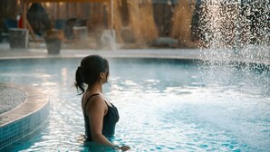 A woman in a swimming pool with water splashing around her.