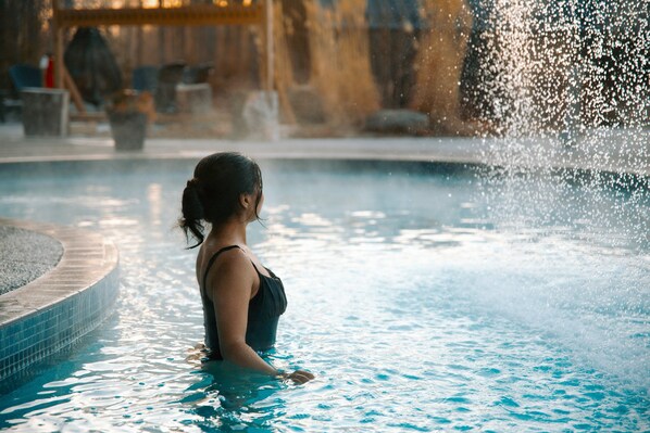 A woman in a swimming pool with water splashing around her.
