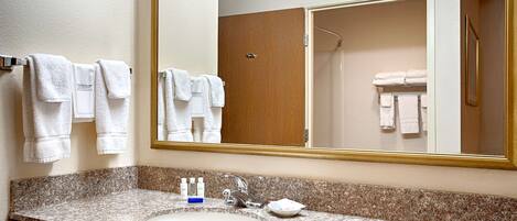 A bathroom with a granite countertop, a sink, a mirror, and a wooden door.