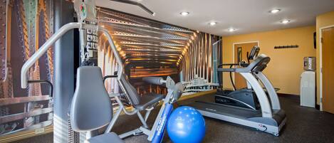 Un gimnasio con equipo de ejercicio, una cinta de correr y una pelota de ejercicio azul.