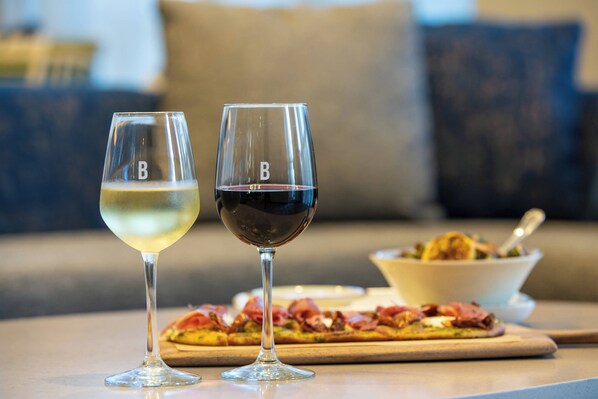 Two wine glasses on a table with a pizza in the background. - Courtyard by Marriott Fort Lauderdale Airport & Cruise Port (Dania Beach)