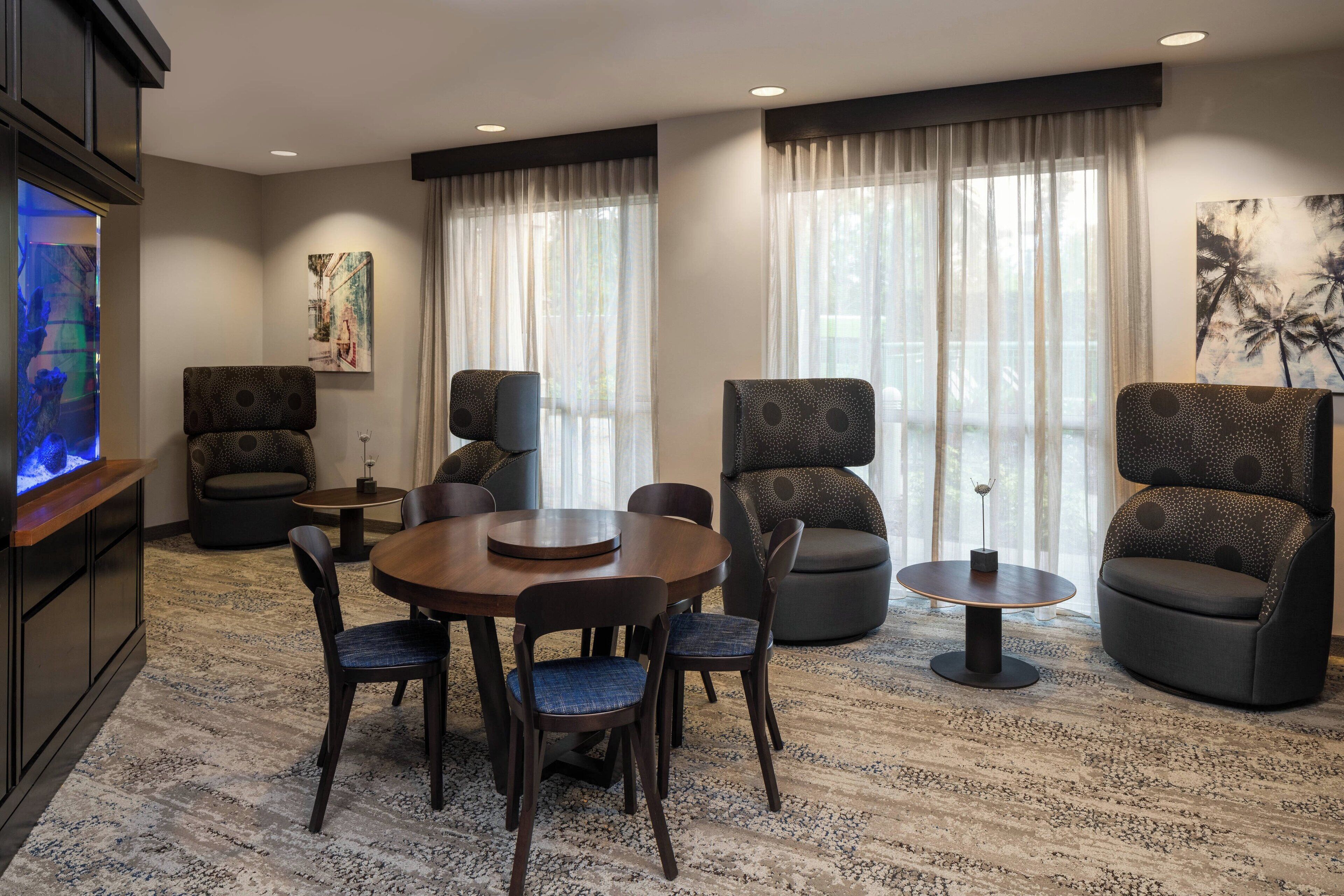 A modern living room with a round wooden table, four chairs, two sofas, and a television.