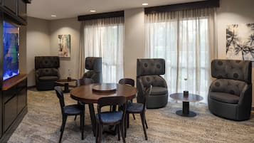 A modern living room with a round wooden table, four chairs, two sofas, and a television.