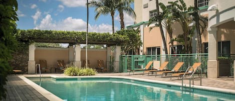 A pool area with lounge chairs and palm trees.