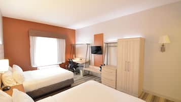 Quarto de hotel com duas camas, uma escrivaninha, uma televisão e um guarda-roupa.