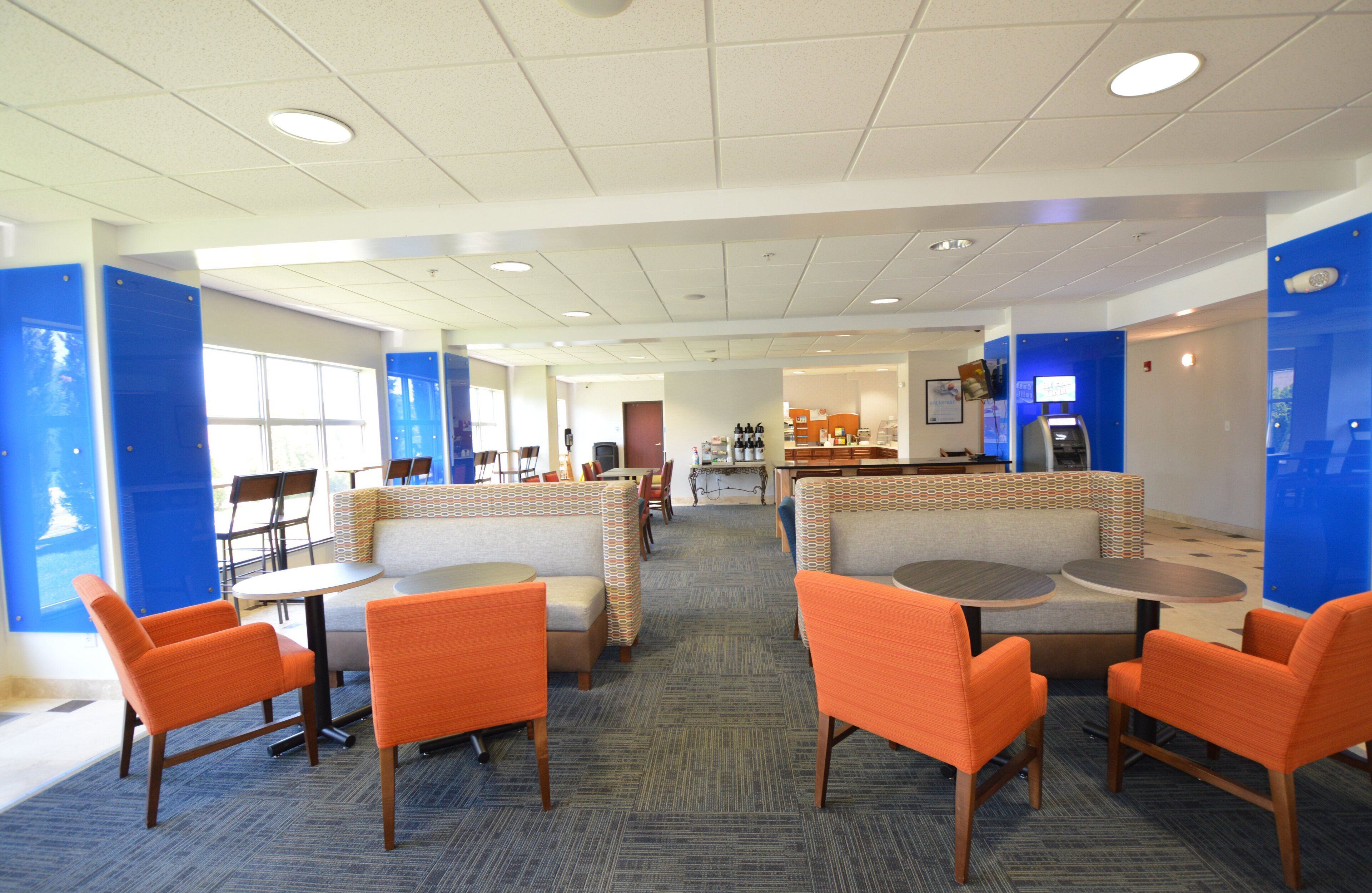 A hotel lobby with seating areas, a reception desk, and a view of the dining area.