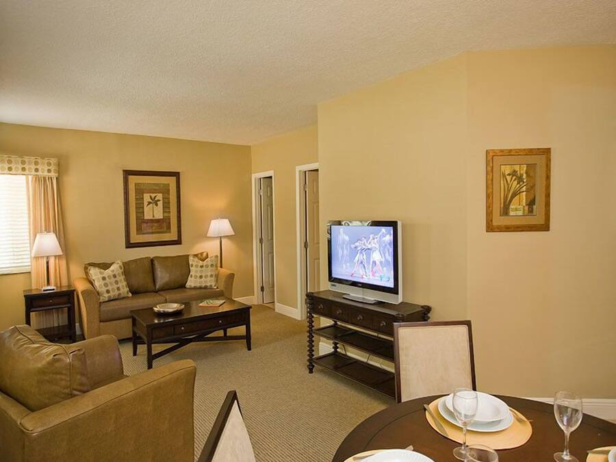 A living room with a sofa, coffee table, TV, and dining table set for two.