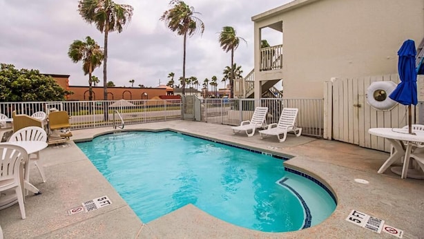 A swimming pool with lounge chairs and a covered seating area. - Ocean Inn South Padre Island (South Padre Island)