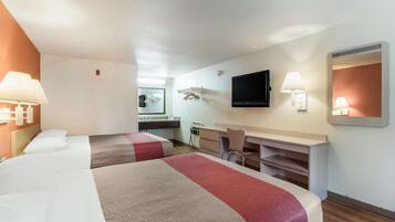 Habitación de hotel con dos camas, un escritorio, una silla, un televisor de pantalla plana y un espejo.