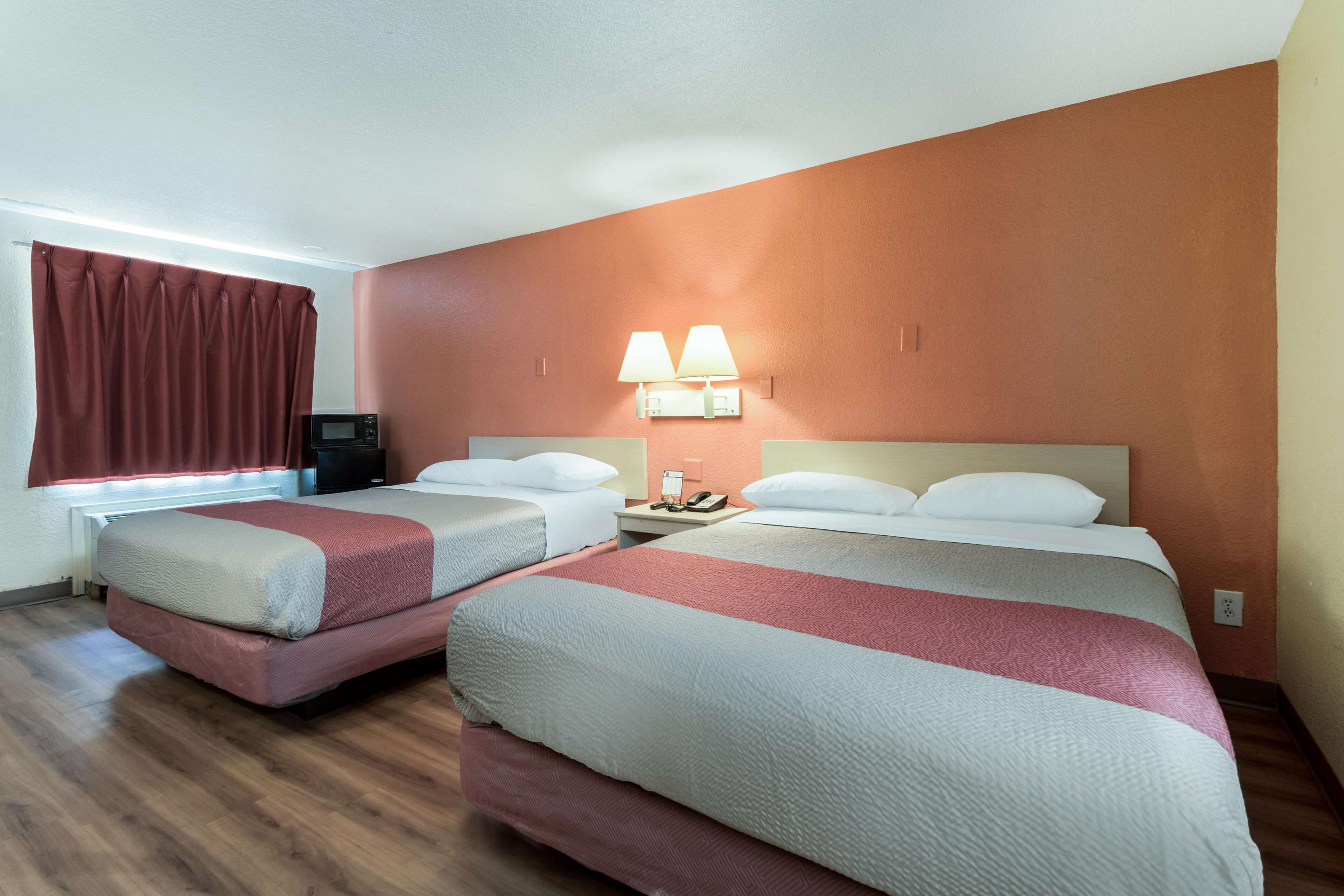 A hotel room with two beds, a TV, a lamp, and a phone on the nightstand.