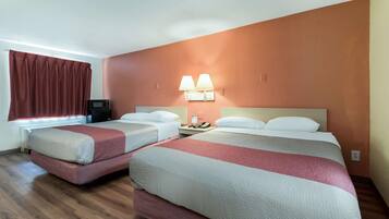 A hotel room with two beds, a TV, a lamp, and a phone on the nightstand.