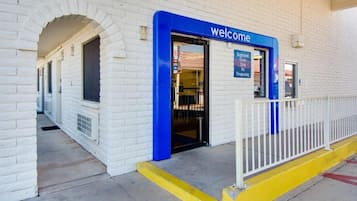 A building entrance with a 'welcome' sign, a gated area, and a pathway leading to the entrance.