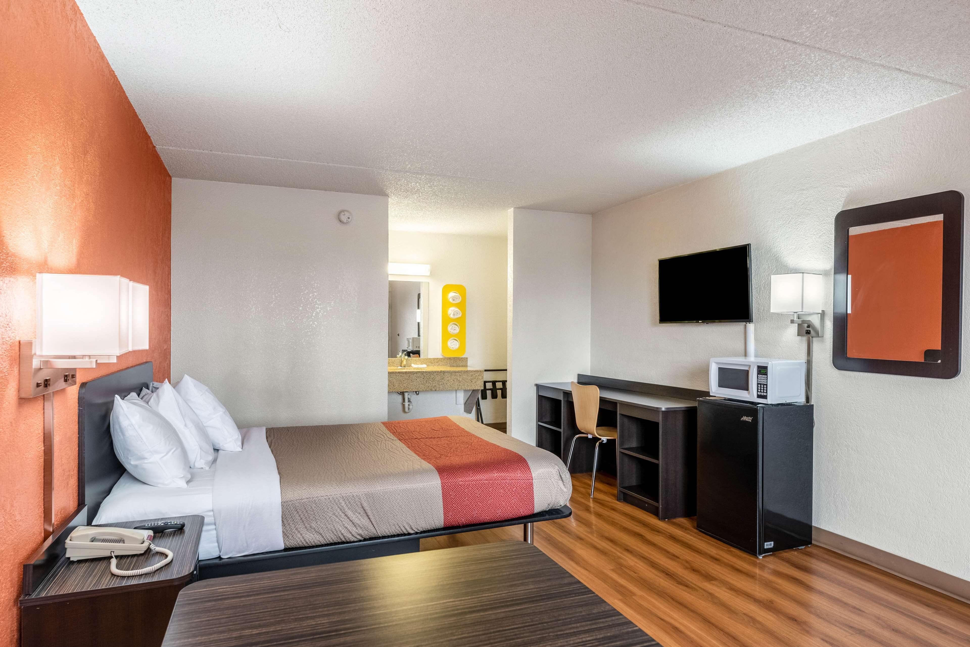 Ein Hotelzimmer mit Bett, Schreibtisch, Mikrowelle und Fernseher.