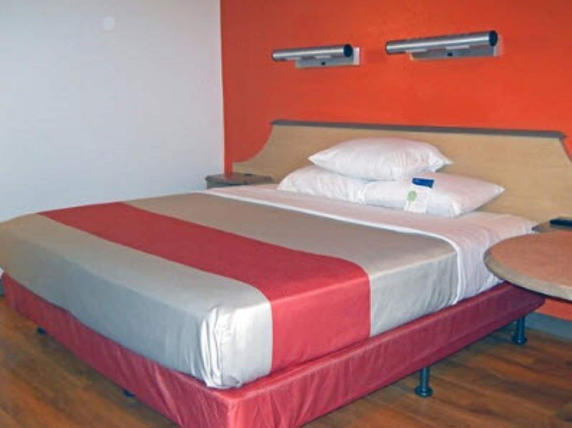 A hotel room with a bed, a nightstand, and a round table.