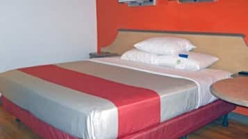 Quarto de hotel com cama, mesa de cabeceira e mesa redonda.