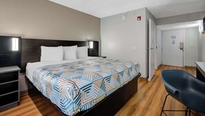 A hotel room with a bed, bedside tables, a desk, and a chair.