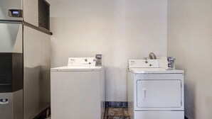 A laundry room with two white front-loading washers and a stainless steel dryer. - Motel 6 Shepherdsville, KY – Louisville South (Shepherdsville)