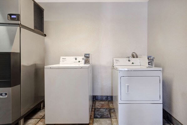 A laundry room with two white front-loading washers and a stainless steel dryer. - Motel 6 Shepherdsville, KY – Louisville South (Shepherdsville)