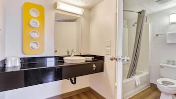 A bathroom with a black countertop, a white sink, and a mirror. There is a shower curtain visible in the background.