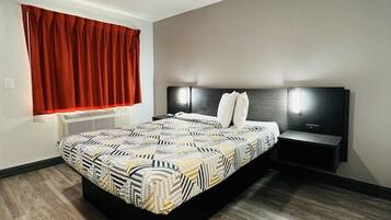 A modern bedroom with a large bed, a nightstand, a wall-mounted TV, and a window with red curtains.