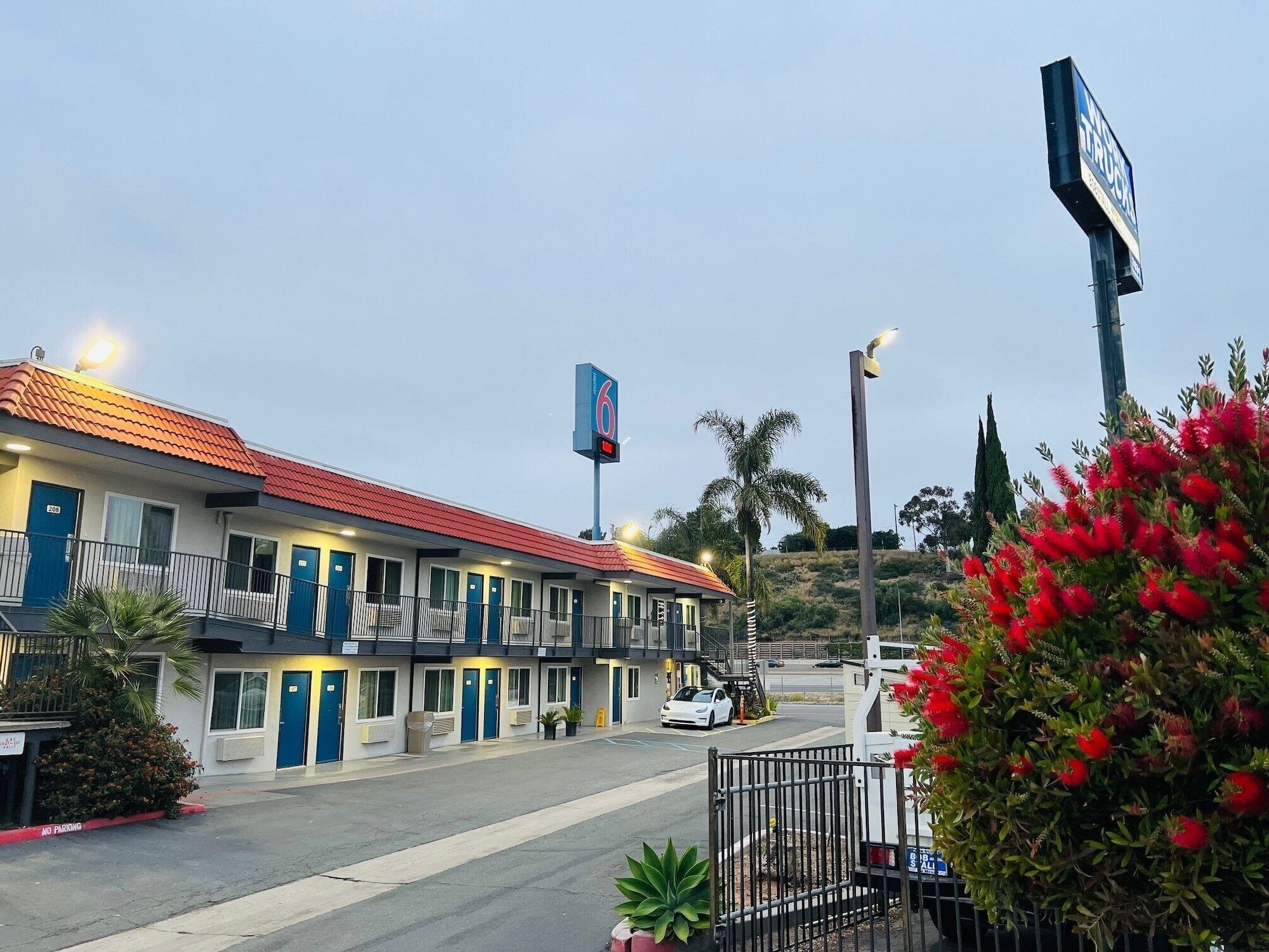 A motel with a red-tiled roof, multiple rooms, and a parking lot.