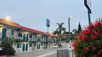 A motel with a red-tiled roof, multiple rooms, and a parking lot.