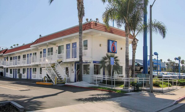 A motel with a red-tiled roof, multiple balconies, and a sign indicating room number 6.