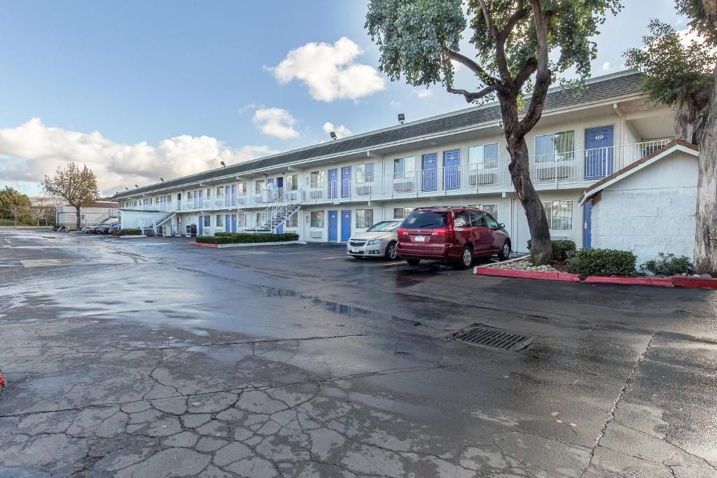 A motel with multiple rooms, a parking lot, and a tree.