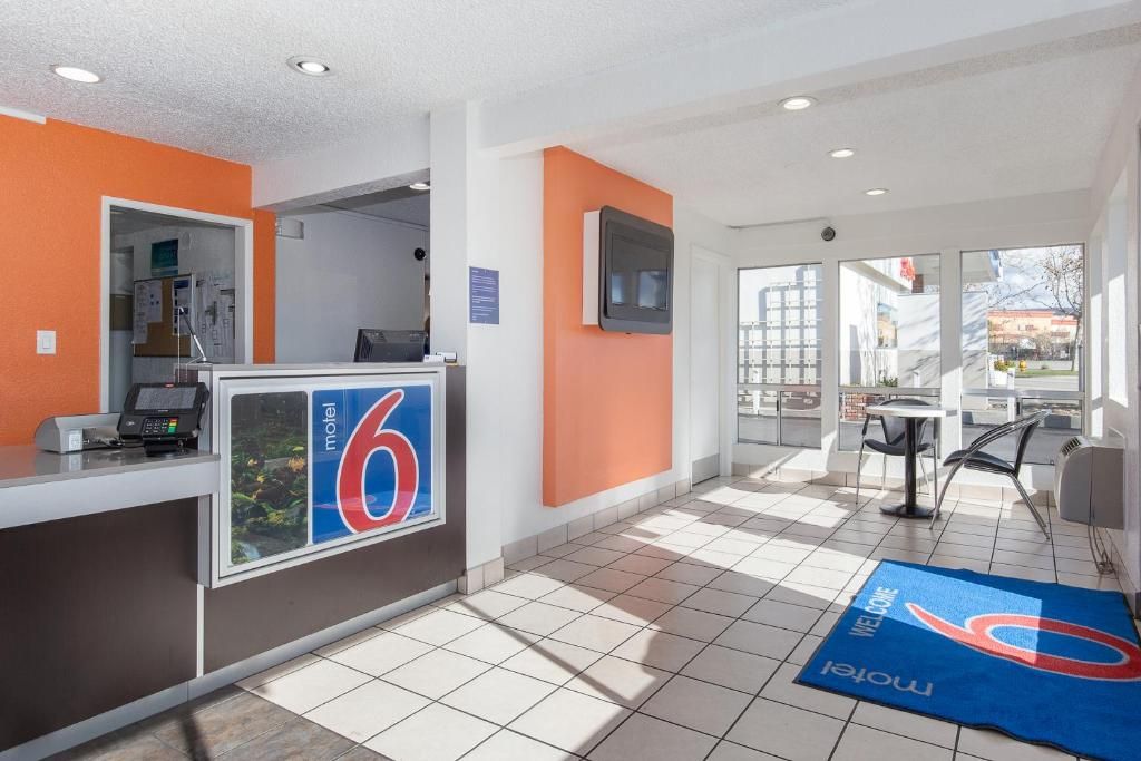 A hotel reception area with a reception desk, a digital display, and a view of the outside.