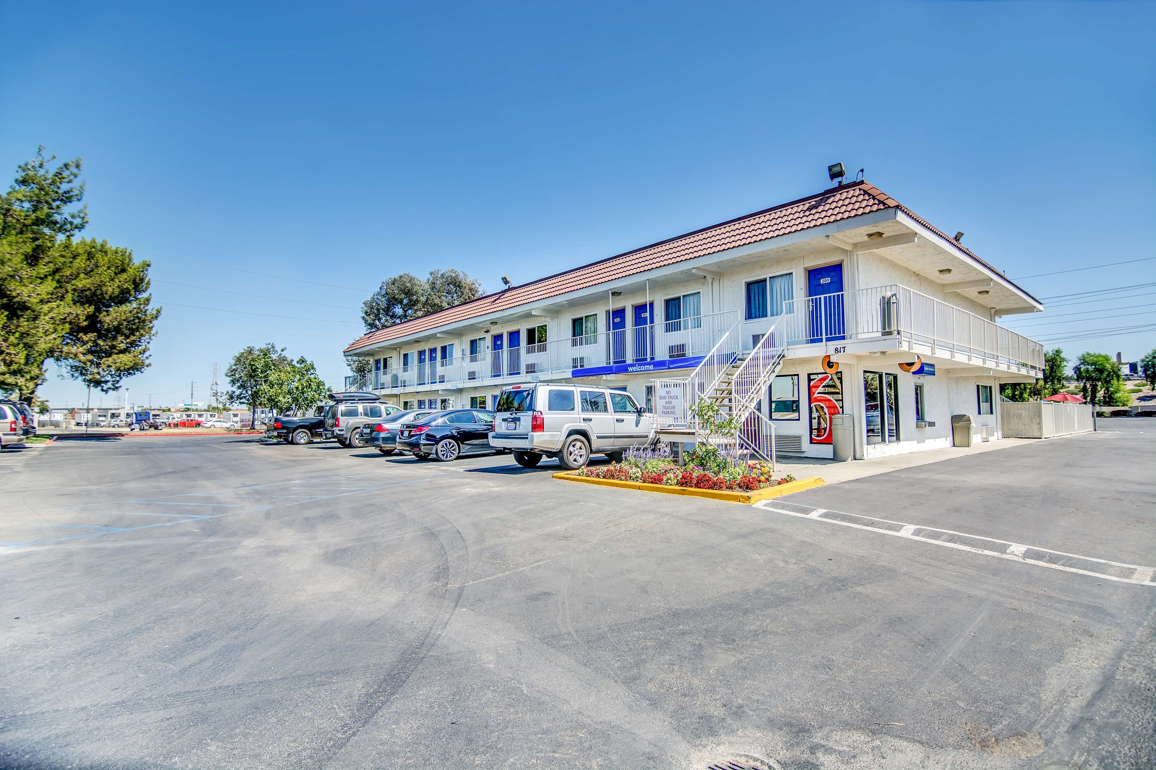 A motel with a red-tiled roof, multiple rooms, and a parking lot.