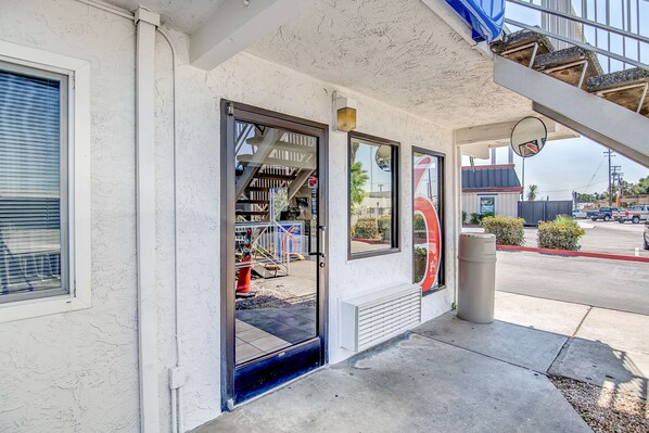 A building entrance with a glass door, a staircase, and a trash can.
