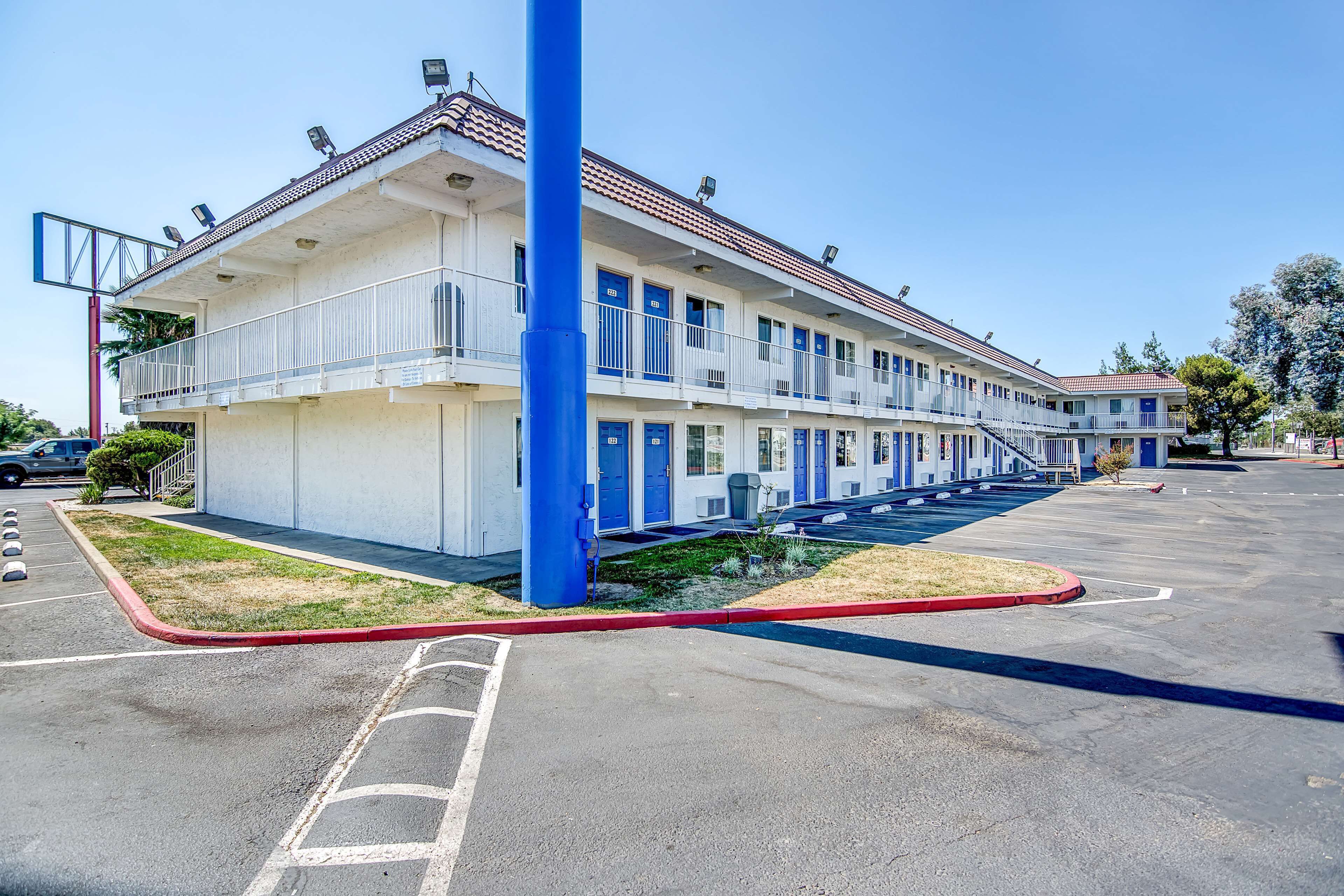 Un motel con struttura a due piani, un parcheggio e una piccola area verde.