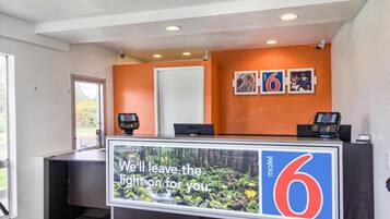 Een receptiebalie van een motel met een groot bord waarop staat: 'We houden het licht voor u aan'.