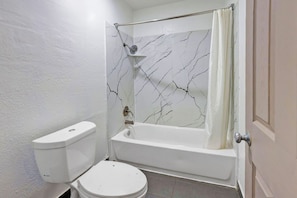 A bathroom with a toilet, bathtub, and shower curtain.