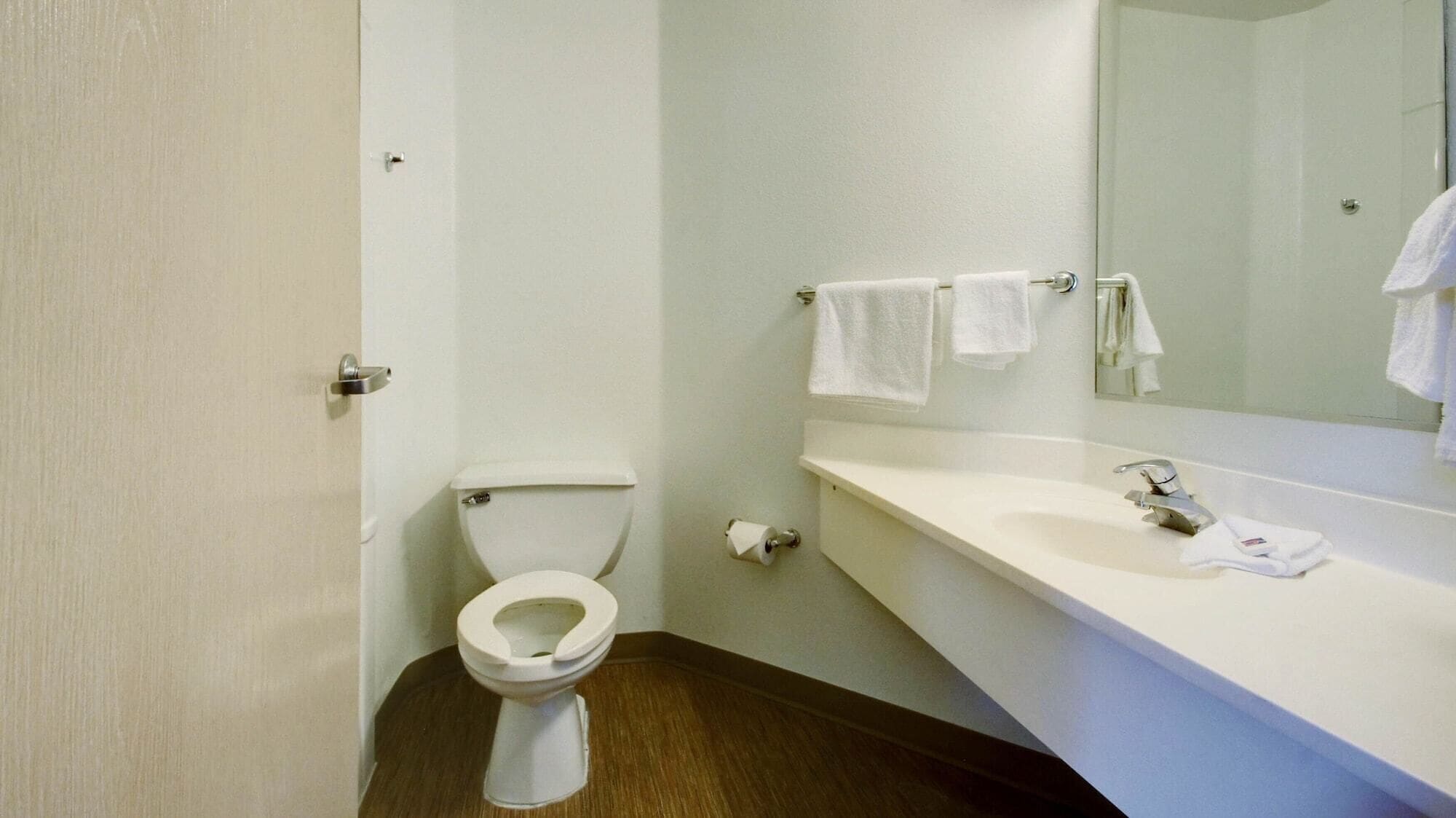 A small, clean bathroom with a toilet, sink, and mirror.