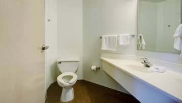 A small, clean bathroom with a toilet, sink, and mirror.