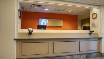 A hotel reception desk with a digital display showing the number 6, a cash register, and a telephone.