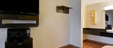 A modern kitchen with a built-in microwave, a flat-screen TV, and a coffee machine.