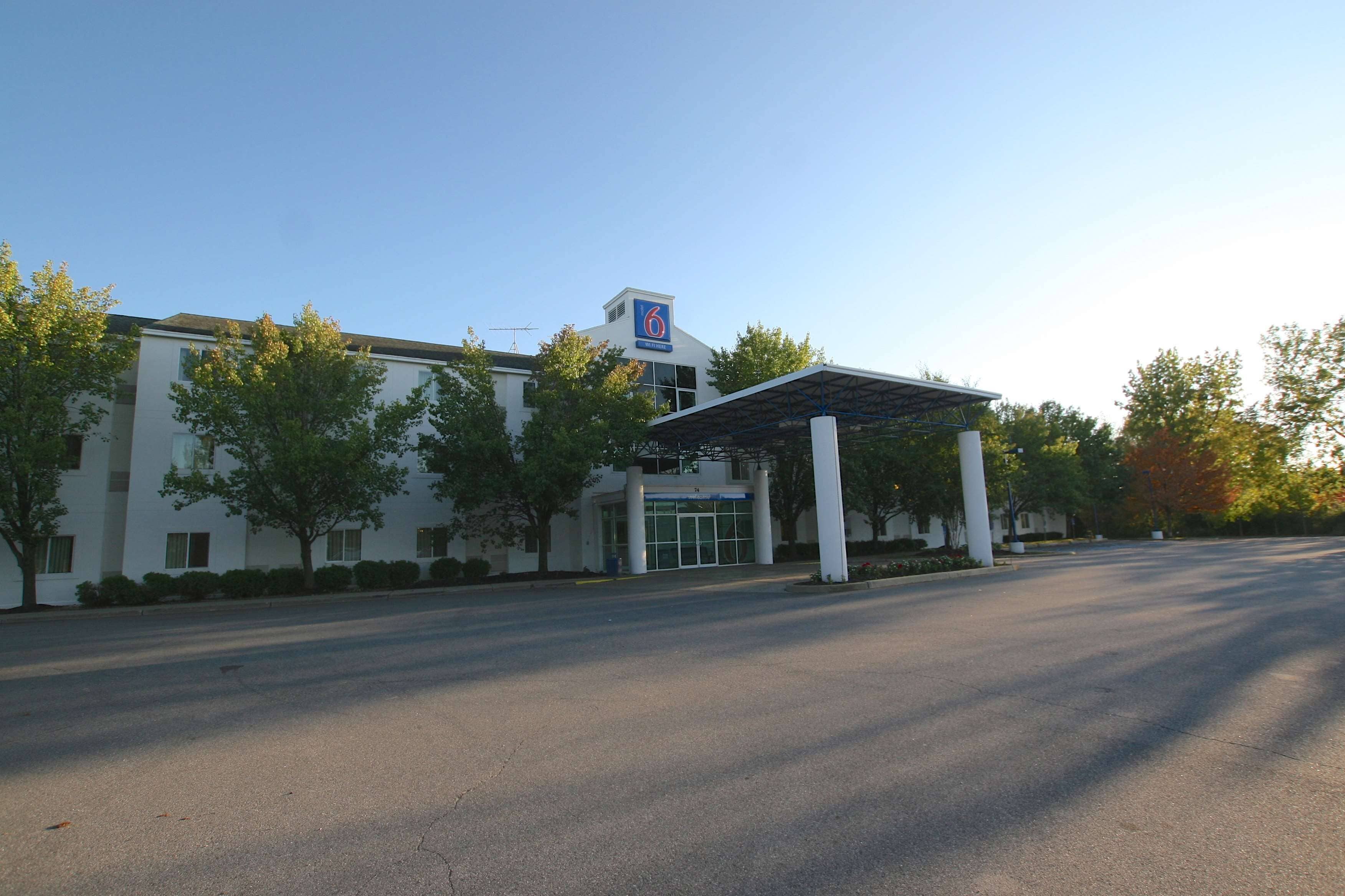 A modern building with a covered entrance, large windows, and a clear sky.