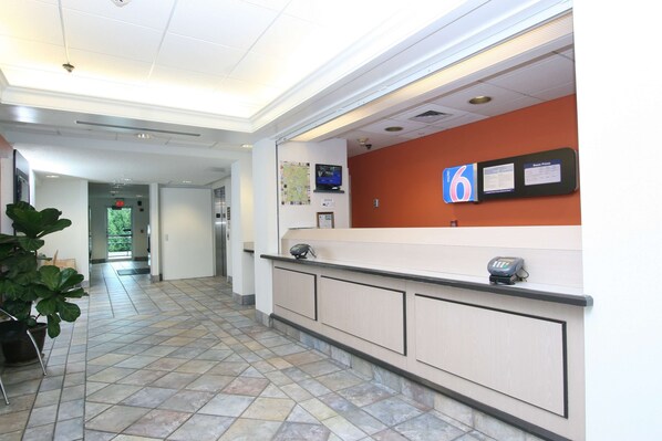 A reception area with a counter, a map, and a digital display. - Motel 6 Colchester, VT - Burlington (Colchester)