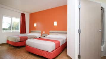 A hotel room with two beds, a window with a view, and a door.