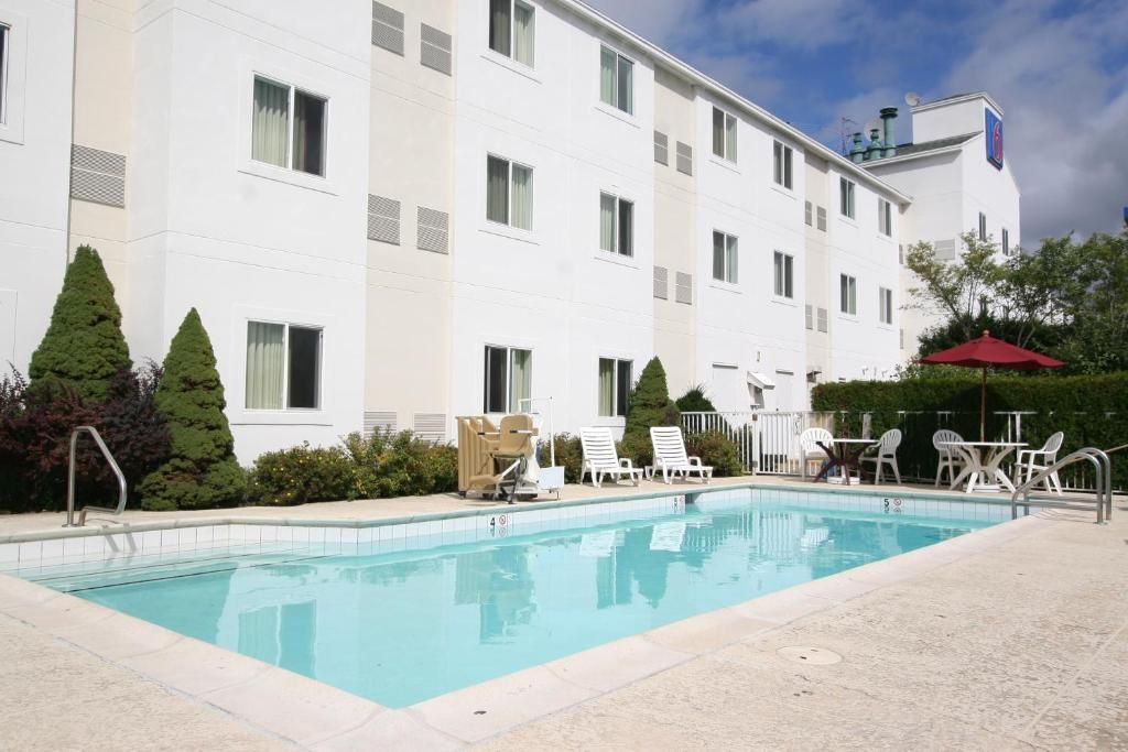 Hotel amb piscina, zona d'estar a l'exterior i façana blanca d'edifici.