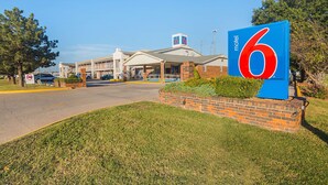 A motel with a prominent '6' sign, a brick facade, and a covered parking area. - Motel 6 Lawton, OK (Lawton)