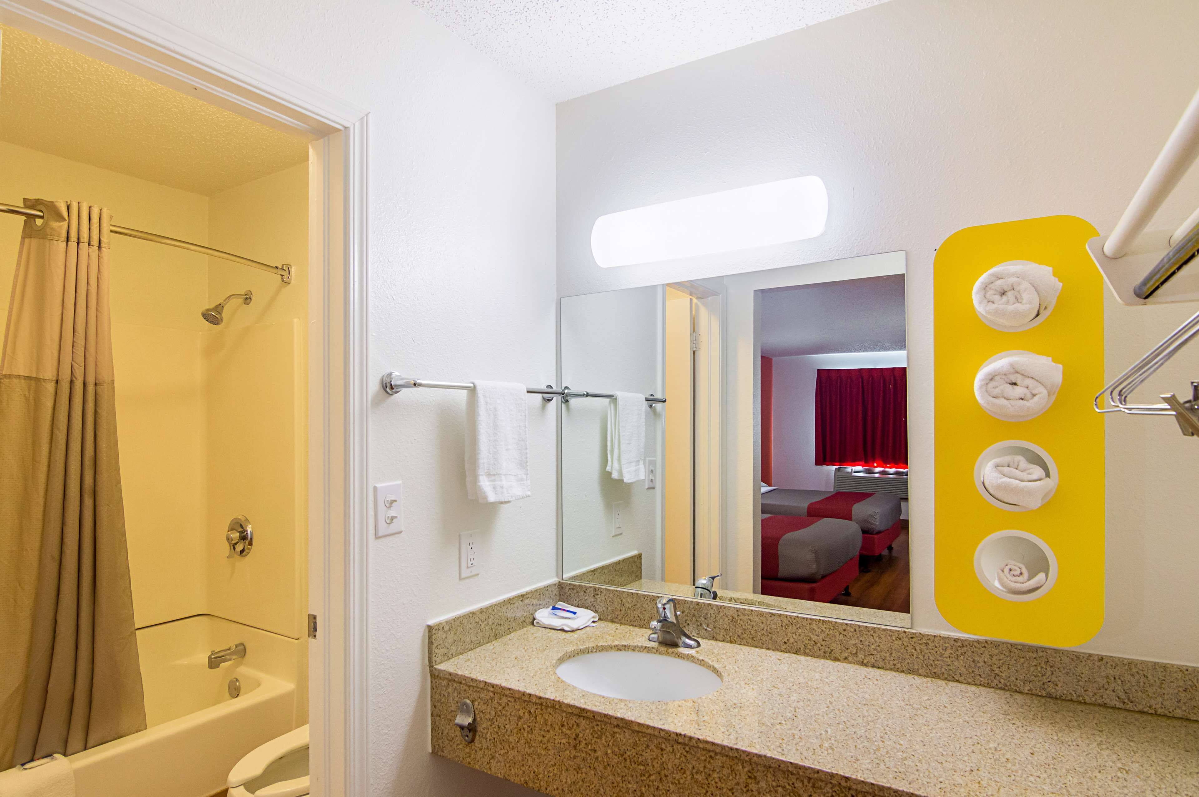 A bathroom with a bathtub, a sink, a mirror, and a towel rack.