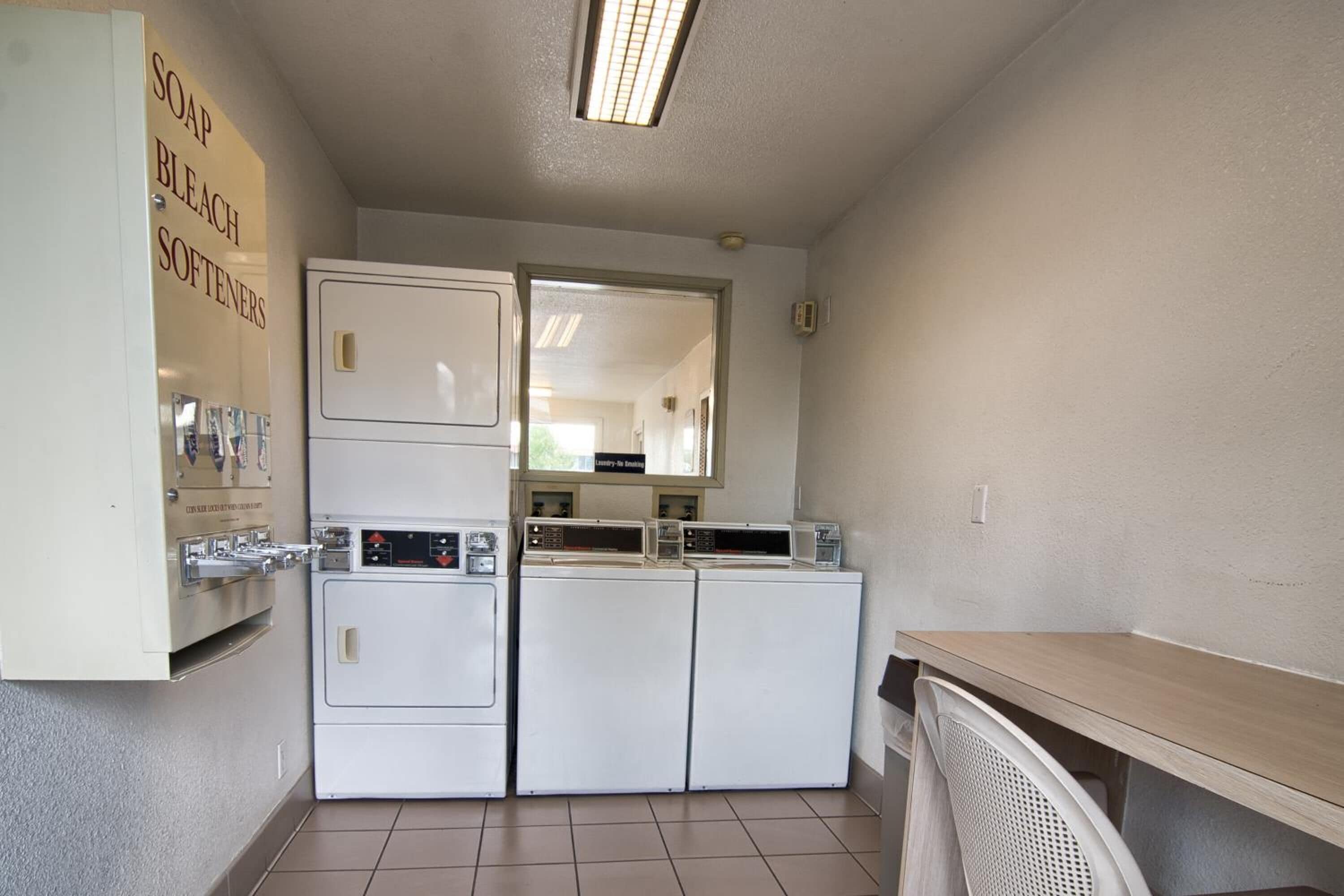 A laundry room with a washing machine, dryer, and a shelf with soap and bleach.