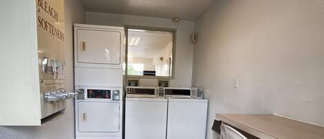 A laundry room with a washing machine, dryer, and a shelf with soap and bleach.