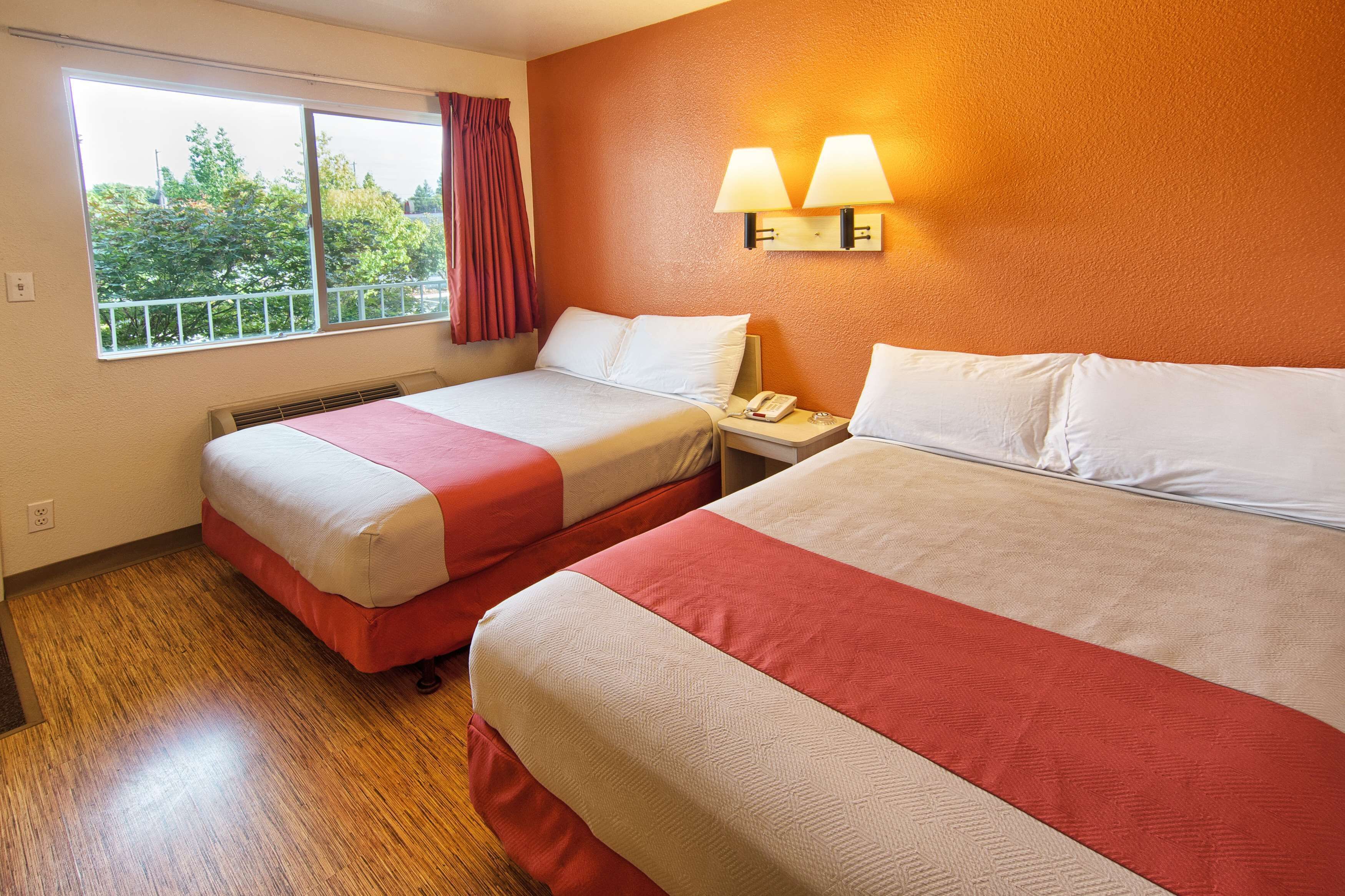 A hotel room with two beds, a window with a view, and a nightstand with a phone.