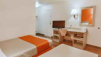 A hotel room with two single beds, a desk with a chair, a television, and a mirror on the wall.